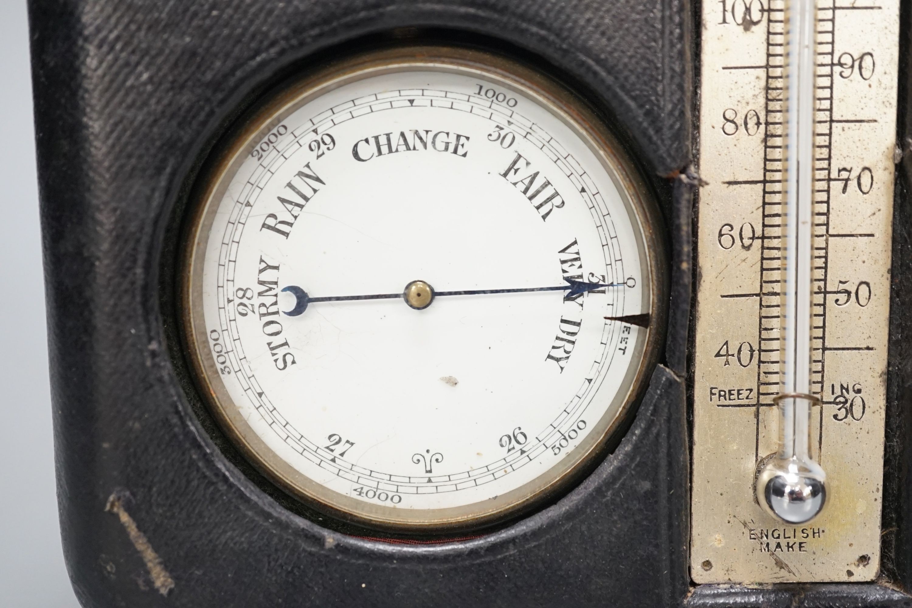 A leather cased pocket watch and barometer with central thermometer, 19.5 cm wide x 13 cms high.